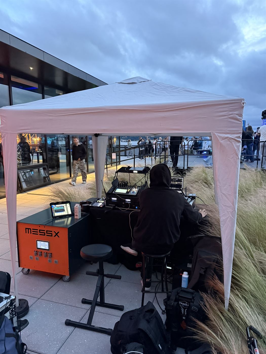 DJ performing at dusk under the tent, with the MESSX 10K and its live monitoring tablet beside the booth